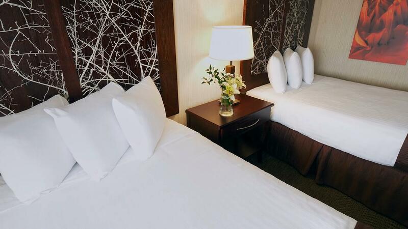 Two guest beds with flowers in a vase on the bedside table.